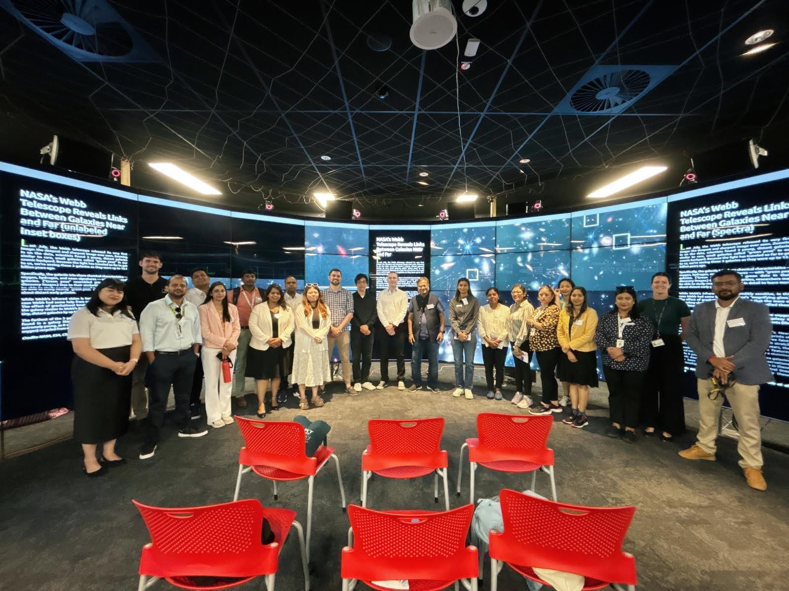 Picture of the delegates in front of the CAVE2 display